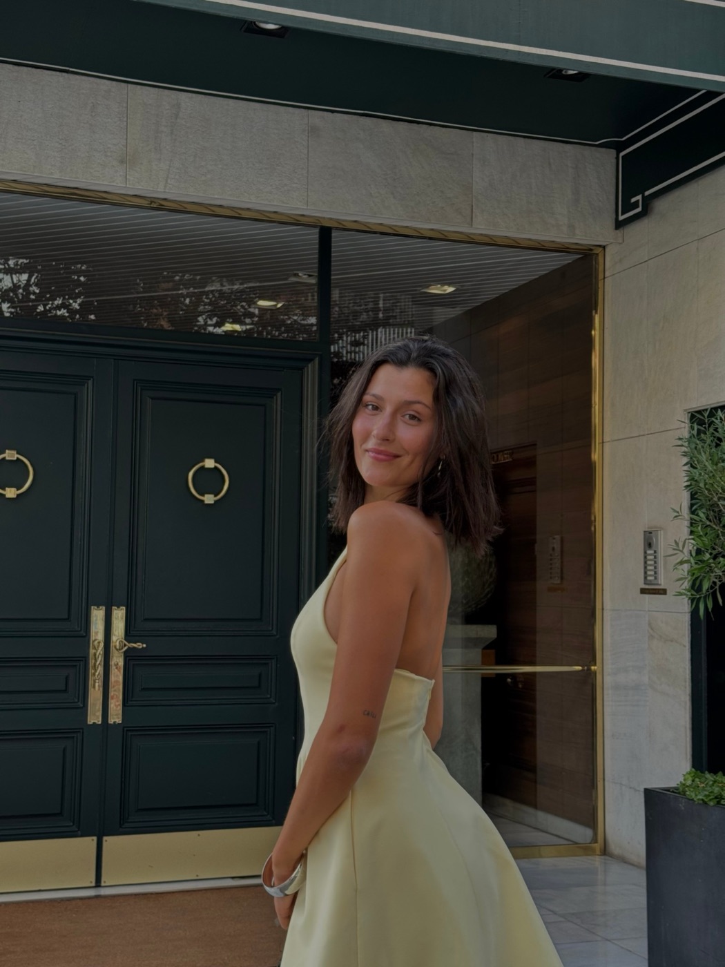 alba con un vestido amarillo delante de una puerta verde